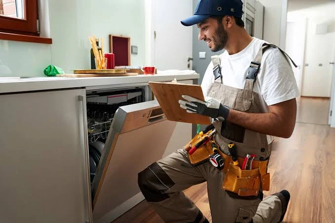 Technician reviewing a clipboard beside an open dishwasher