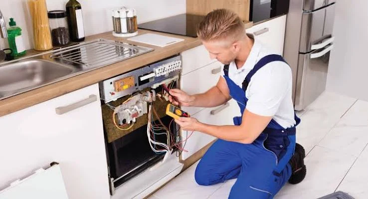 Technician testing dishwasher wiring with a multimeter
