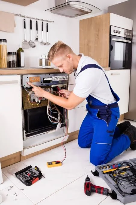 Technician inspecting dishwasher electrical connections with tools nearby